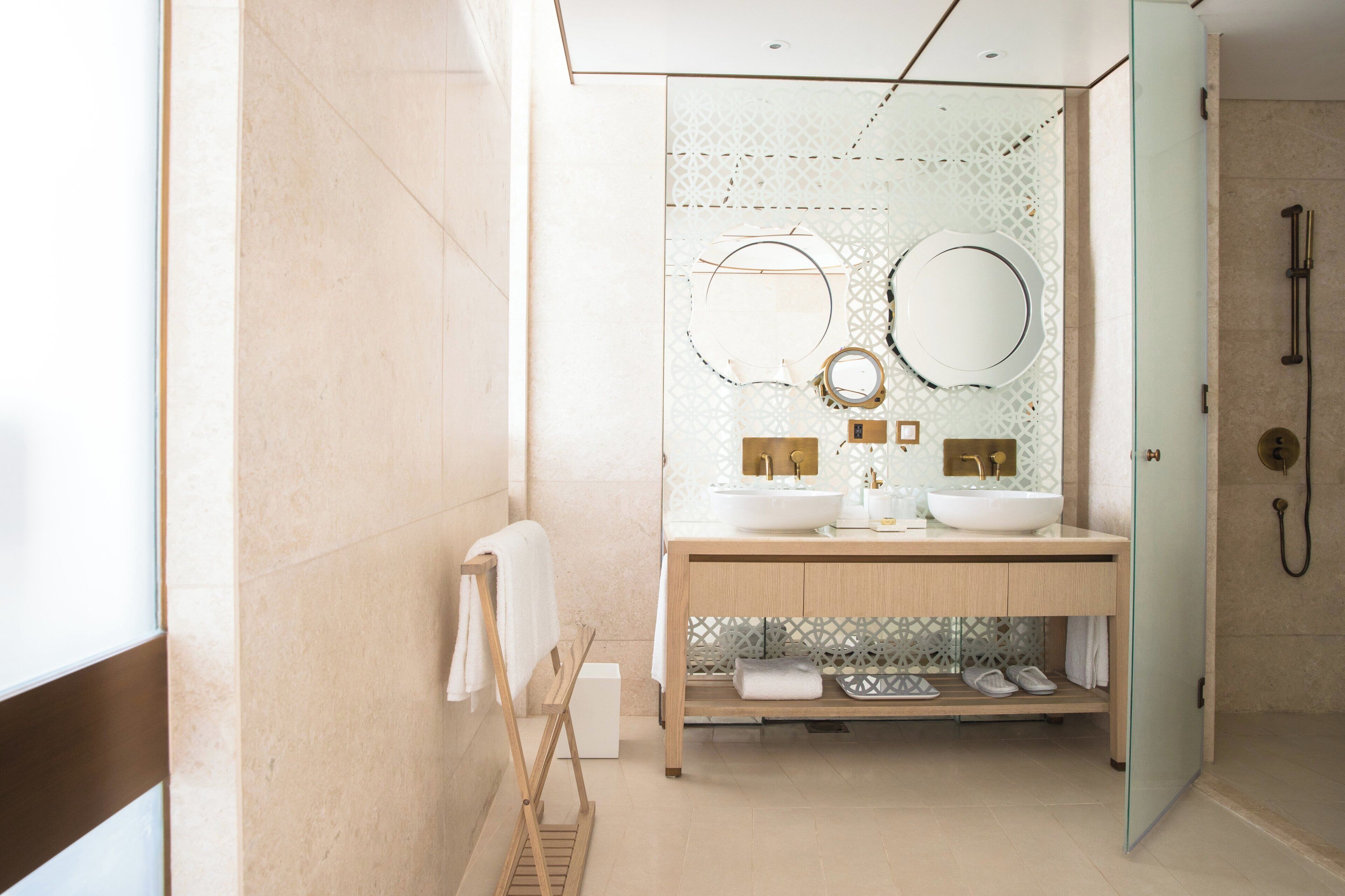 Een moderne badkamer met twee wasbakken, een douche en een glazen wastafelmeubel.