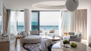 A modern living room with a large sofa, round coffee table, and a view of the ocean. - Jumeirah Saadiyat Island Abu Dhabi (Abu Dhabi)