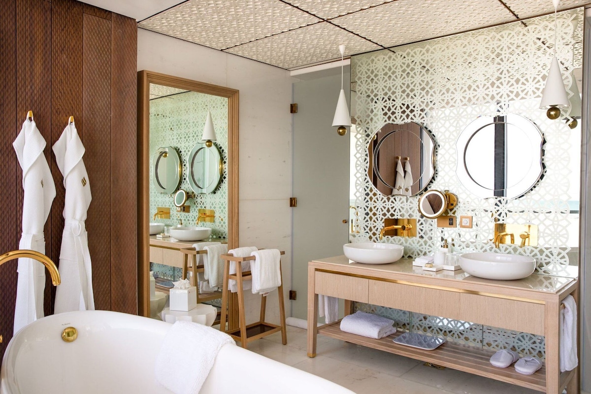 A modern bathroom with a large mirror, two sinks, and a vanity.