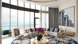 A modern living room with a large window overlooking the beach, a sofa set, a coffee table, and a painting on the wall. - Jumeirah Saadiyat Island Abu Dhabi (Abu Dhabi)