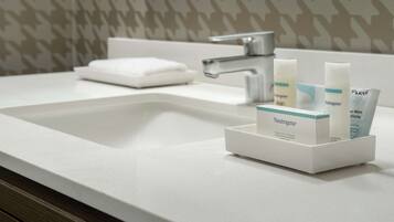 A bathroom sink with a white countertop, a silver faucet, and a Neutrogena product organizer.