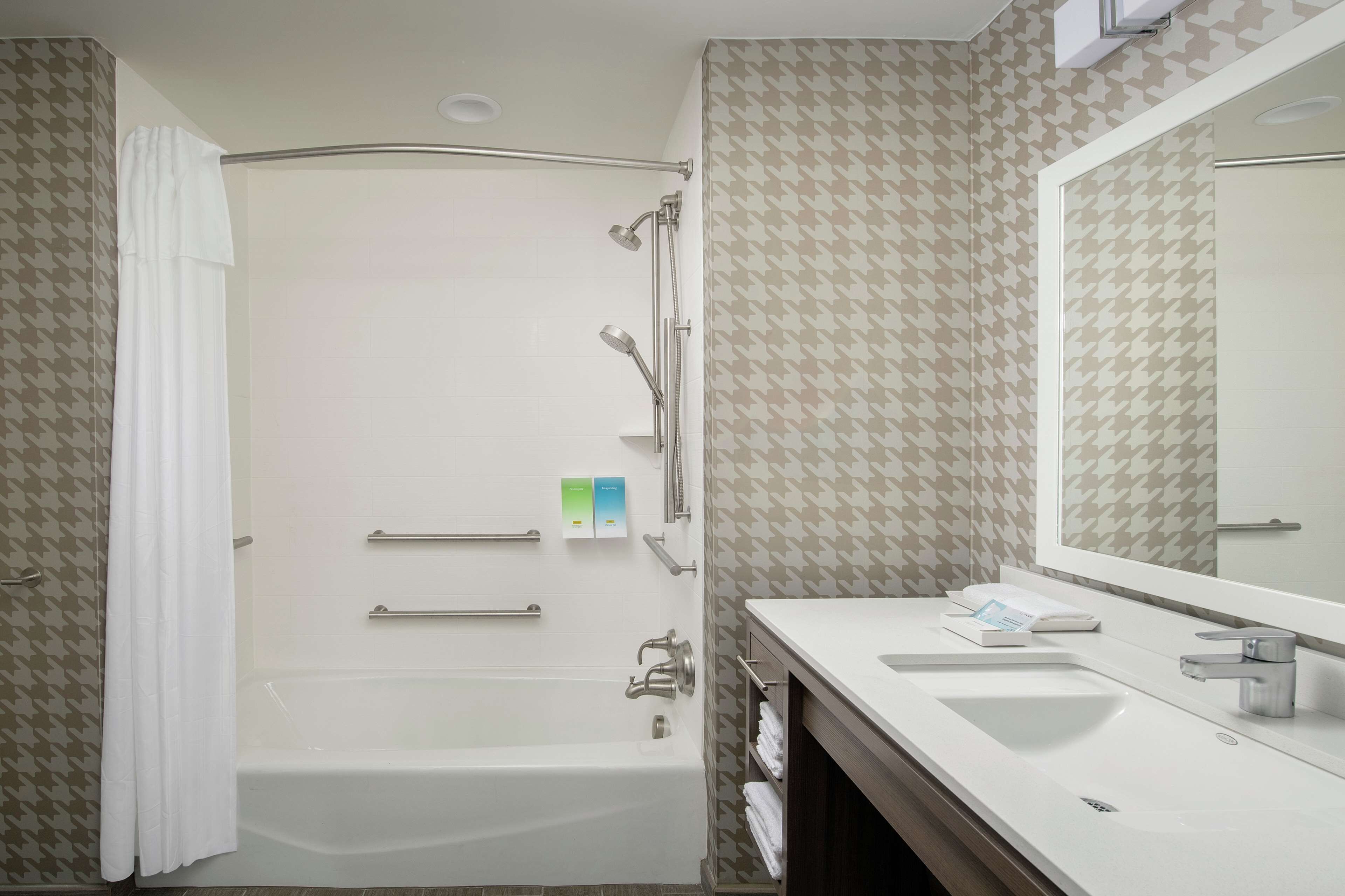 Un baño moderno con bañera, ducha y tocador con un espejo grande.