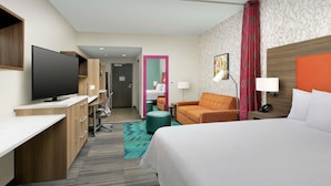 Een hotelkamer met een bed, bureau, televisie en zithoek.