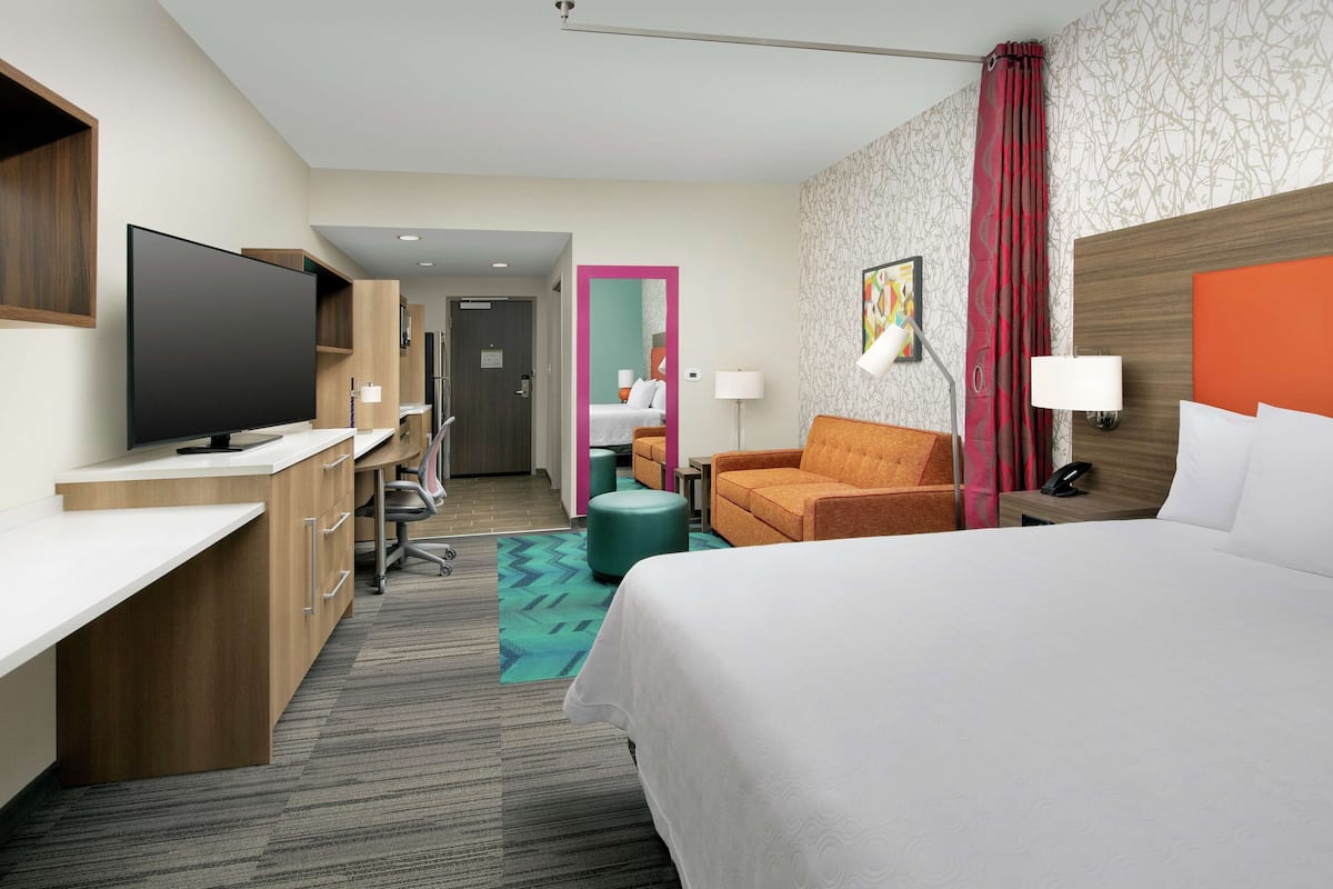 Une chambre d’hôtel comprenant un lit, un bureau, une télévision et un coin salon.