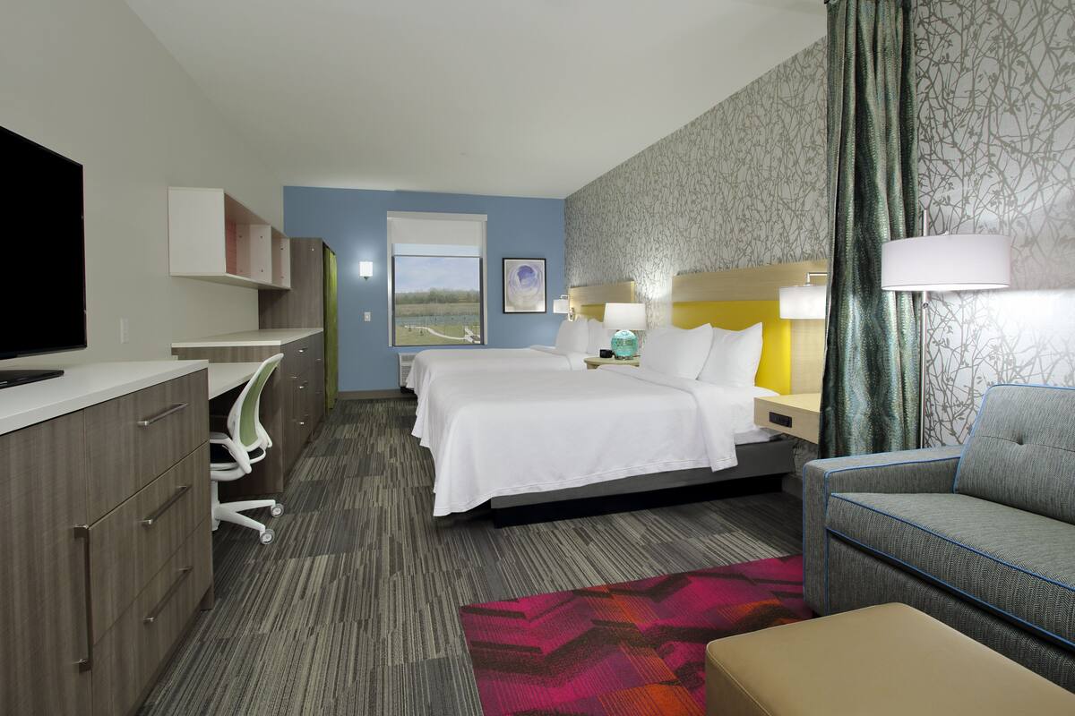 Une chambre d’hôtel équipée d ’un lit, d’un bureau, d’une chaise, d’une télévision et d’une fenêtre donnant sur un paysage agréable.