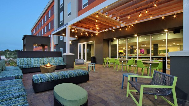 An outdoor patio area with seating, a fire pit, and string lights. - Home2 Suites by Hilton Port Arthur, TX (Port Arthur)