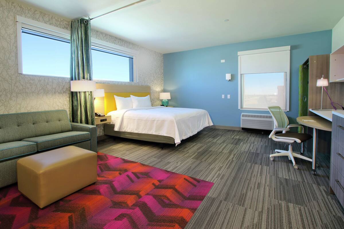 Une chambre d’hôtel avec un lit, un canapé, un bureau et une chaise.