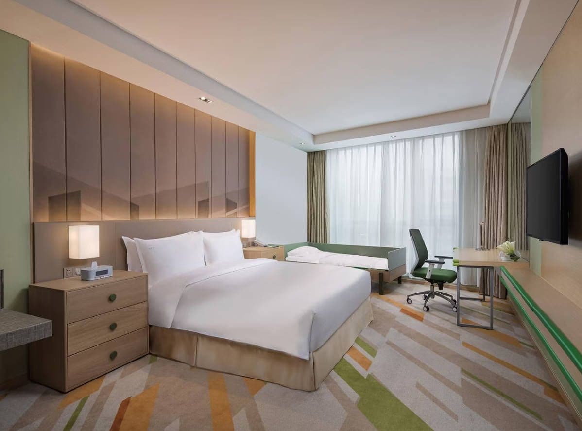 Une chambre d’hôtel avec un grand lit, un bureau, une chaise, une télévision et une table de chevet.
