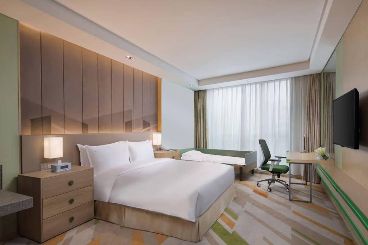 Une chambre d’hôtel avec un grand lit, un bureau, une chaise, une télévision et une table de chevet.