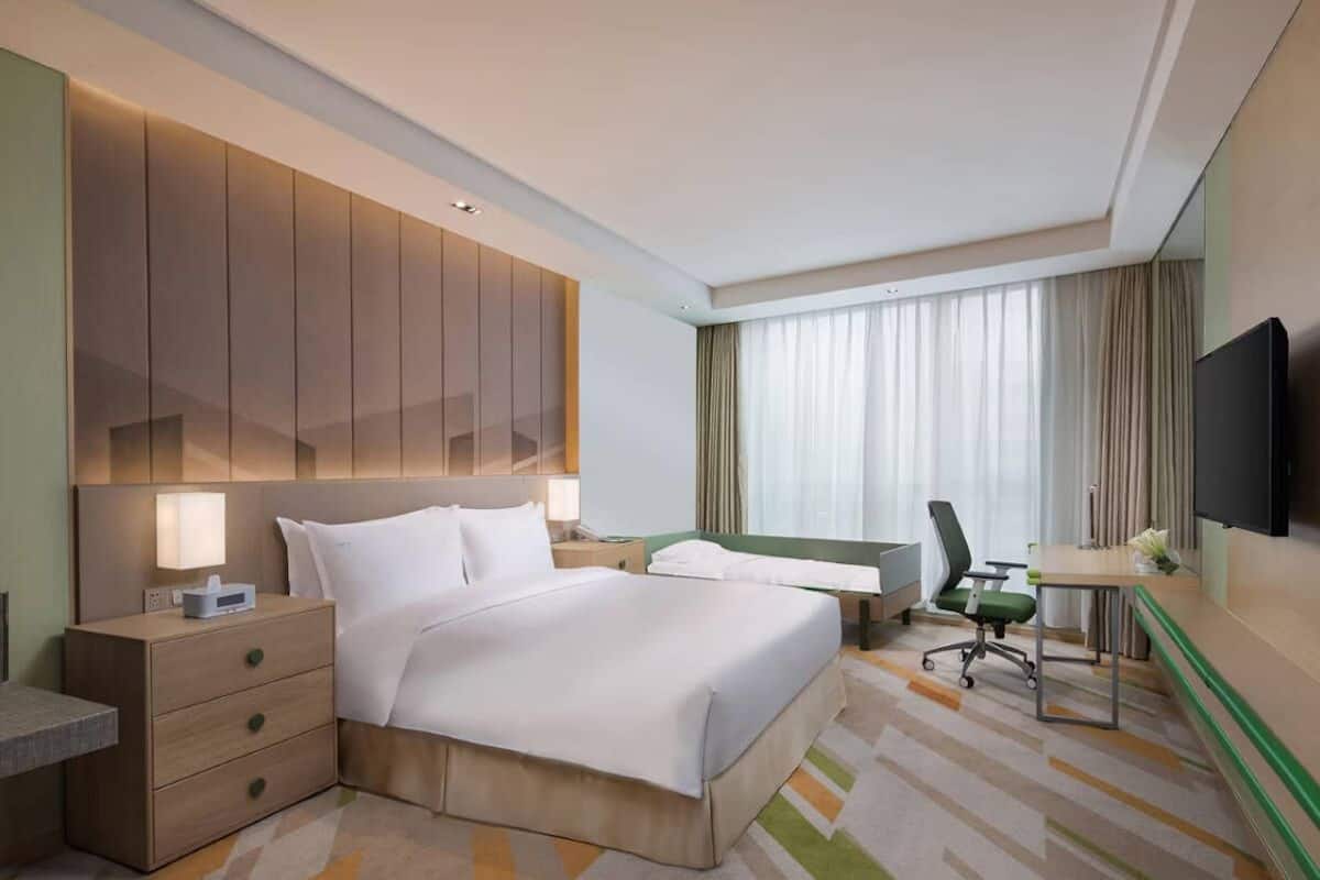 Une chambre d’hôtel avec un grand lit, un bureau, une chaise, une télévision et une table de chevet.