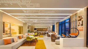 Eine moderne Hotelhalle mit einer langen Couch, gelben Stühlen und einer Bar.