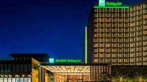 Ein Holiday Inn Hotel mit moderner Fassade, beleuchteter Beschilderung und einem gut ausgeleuchteten Eingang.