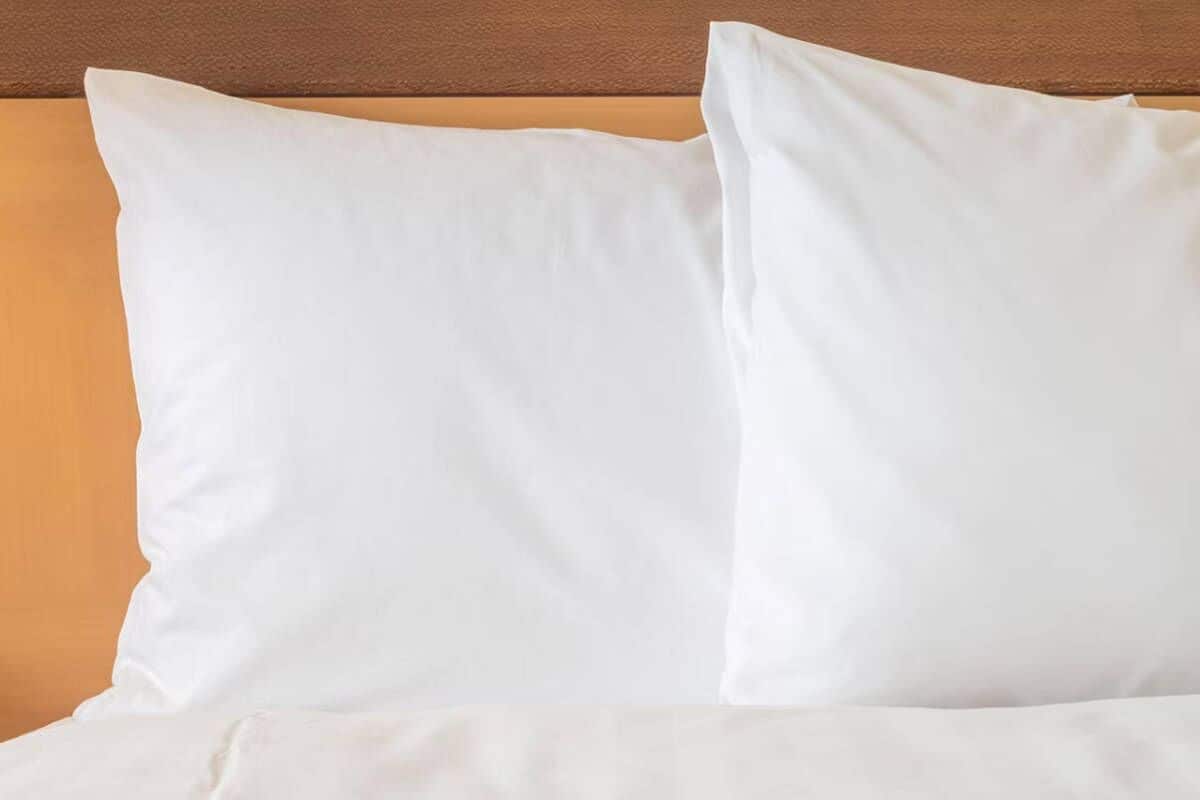 Un lit avec une literie blanche et une tête de lit en bois.
