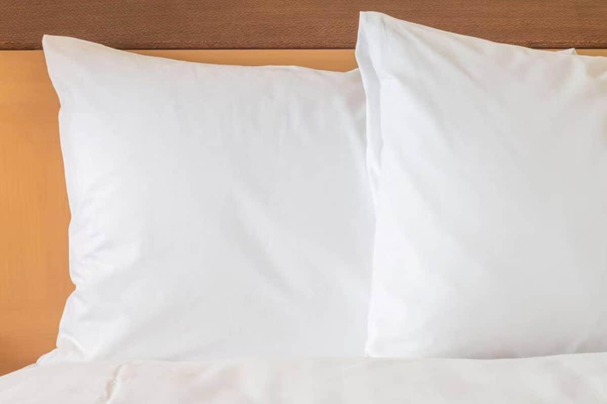 Un lit avec une literie blanche et une tête de lit en bois.
