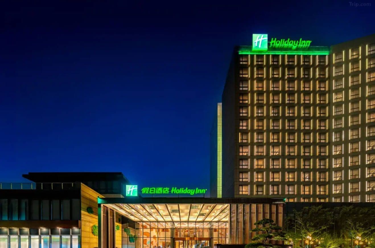 A Holiday Inn hotel with a modern facade, illuminated signage, and a well-lit entrance.