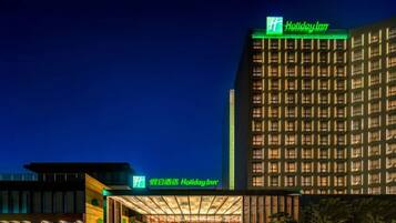 A Holiday Inn hotel with a modern facade, illuminated signage, and a well-lit entrance.