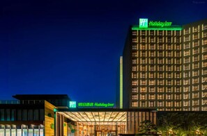 Ein Holiday Inn Hotel mit moderner Fassade, beleuchteter Beschilderung und einem gut ausgeleuchteten Eingang.