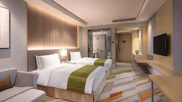 A hotel room with two beds, a sofa, a TV, and a bathroom visible through a glass door.