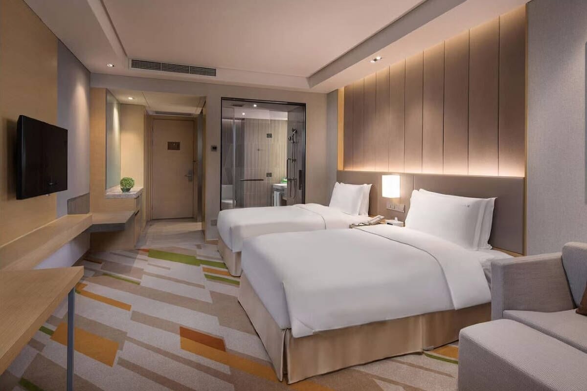 Une chambre d’hôtel avec deux lits, une télévision, un bureau et un espace douche.