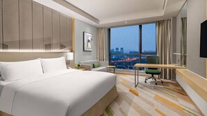 Een moderne hotelkamer met een groot bed, een bureau en uitzicht op de stad.