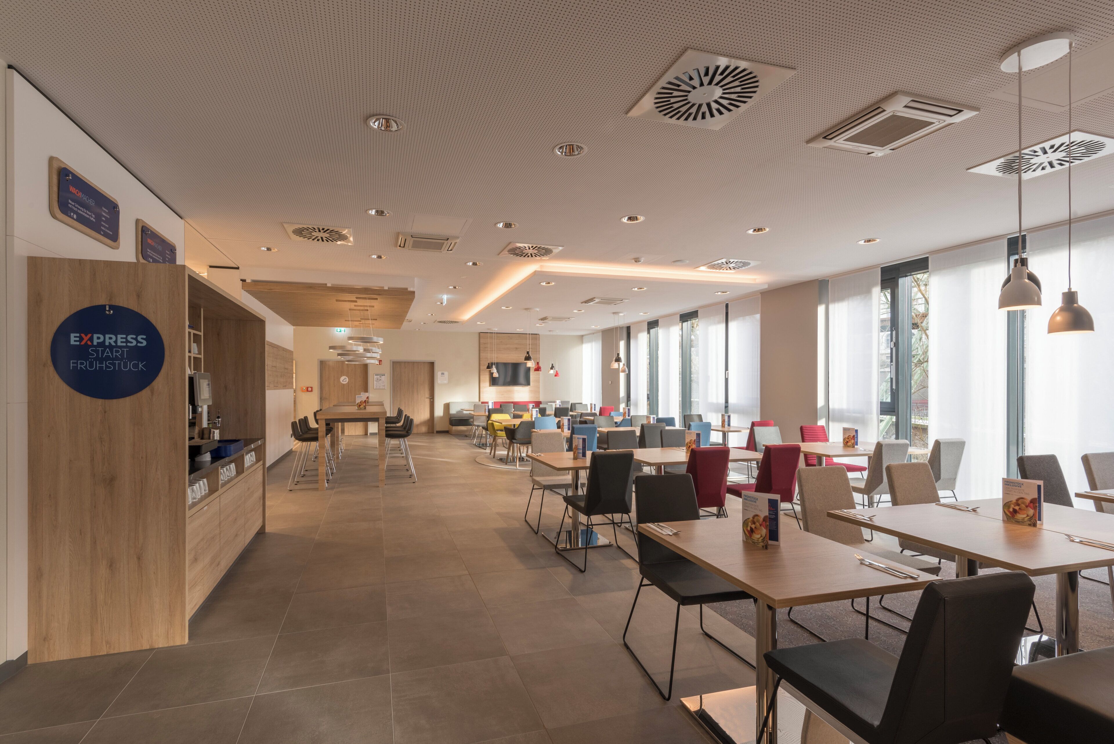 A modern interior with a reception desk, multiple seating areas, and large windows allowing natural light.