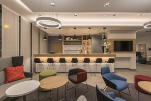 A modern hotel lobby with a bar area, seating arrangements, and a flat-screen TV. - Holiday Inn Express Wuppertal - Hauptbahnhof by IHG (Wuppertal)