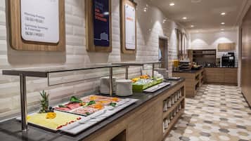 A buffet area with various food options and a clock displaying operating hours.