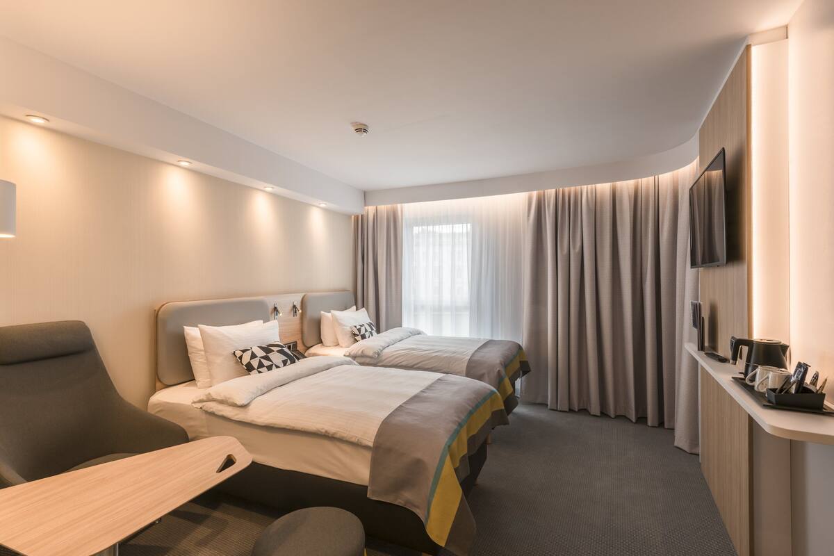 Une chambre d’hôtel moderne avec deux lits, un bureau et une télévision.