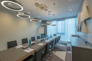 Un salón de conferencias con una larga mesa, sillas y una pizarra.