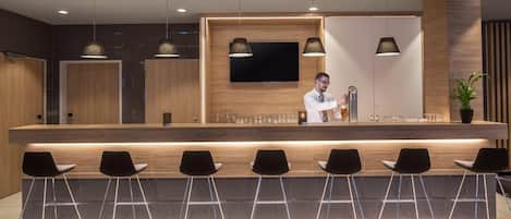 A modern bar area with a bartender, bar counter, and seating.