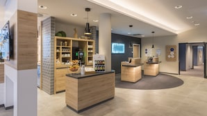 A modern reception area with a central desk, a coffee station, and a wall-mounted display. - Holiday Inn Express Wuppertal - Hauptbahnhof by IHG (Wuppertal)