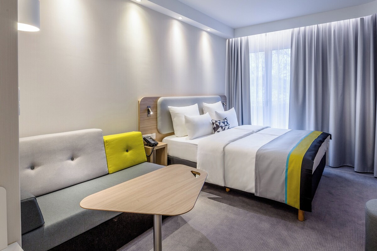 Een hotelkamer met een bed, een bank, een klein tafeltje en een televisie.