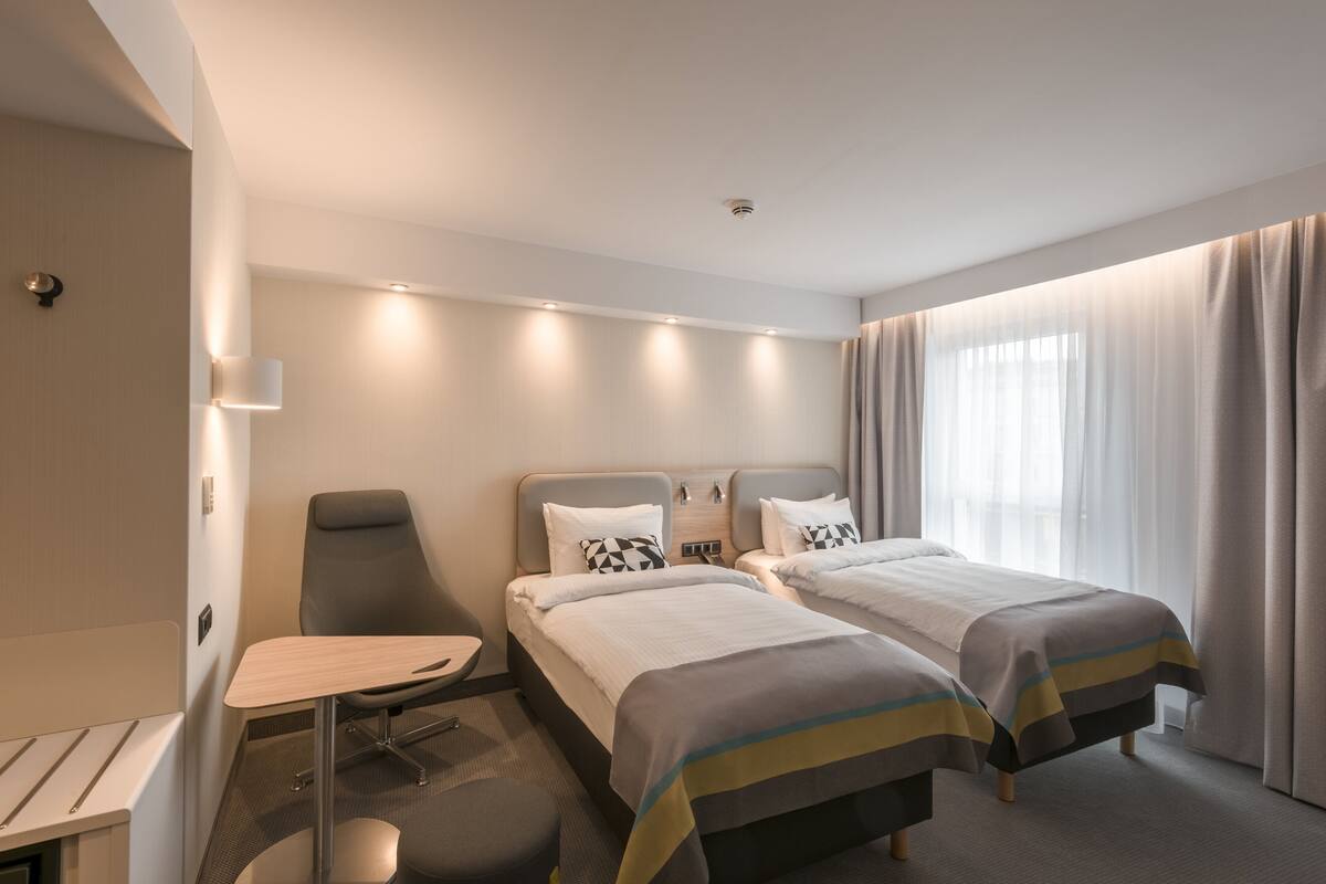 Une chambre d’hôtel avec deux lits, un bureau et une chaise.