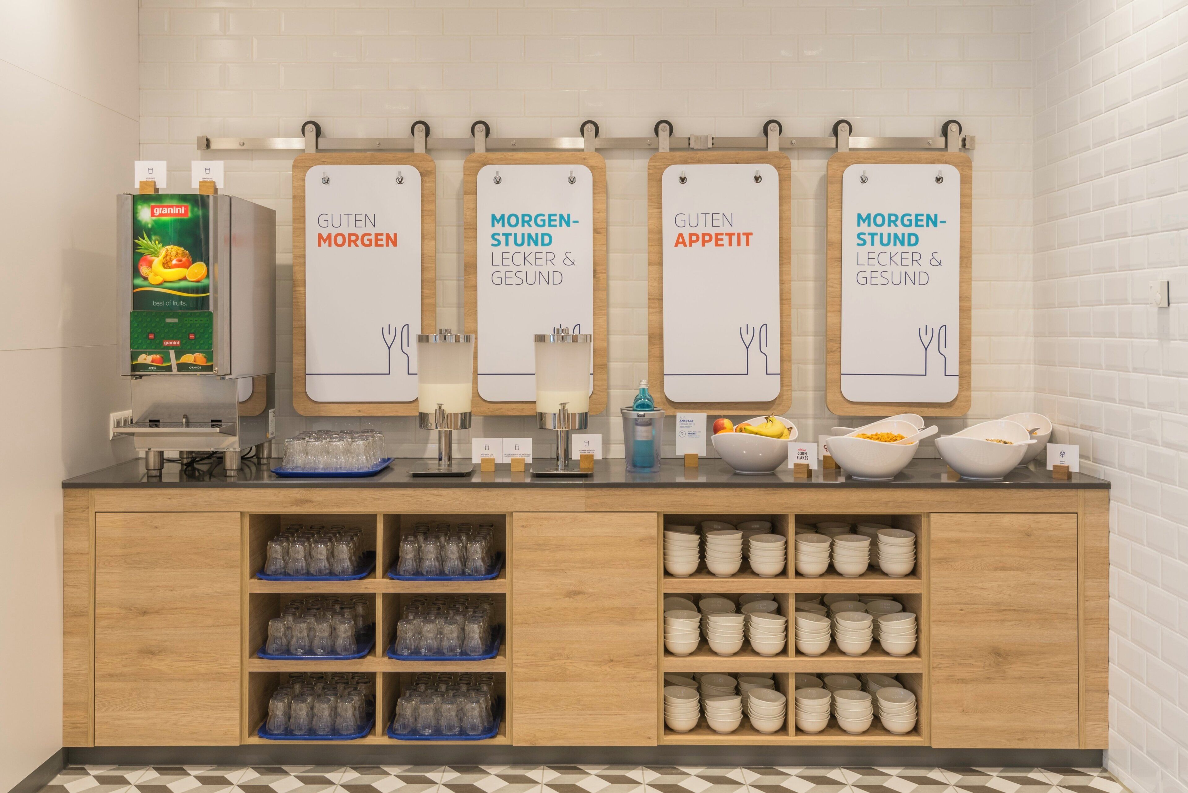A breakfast station with four labeled dispensers, a fruit dispenser, and a coffee machine.