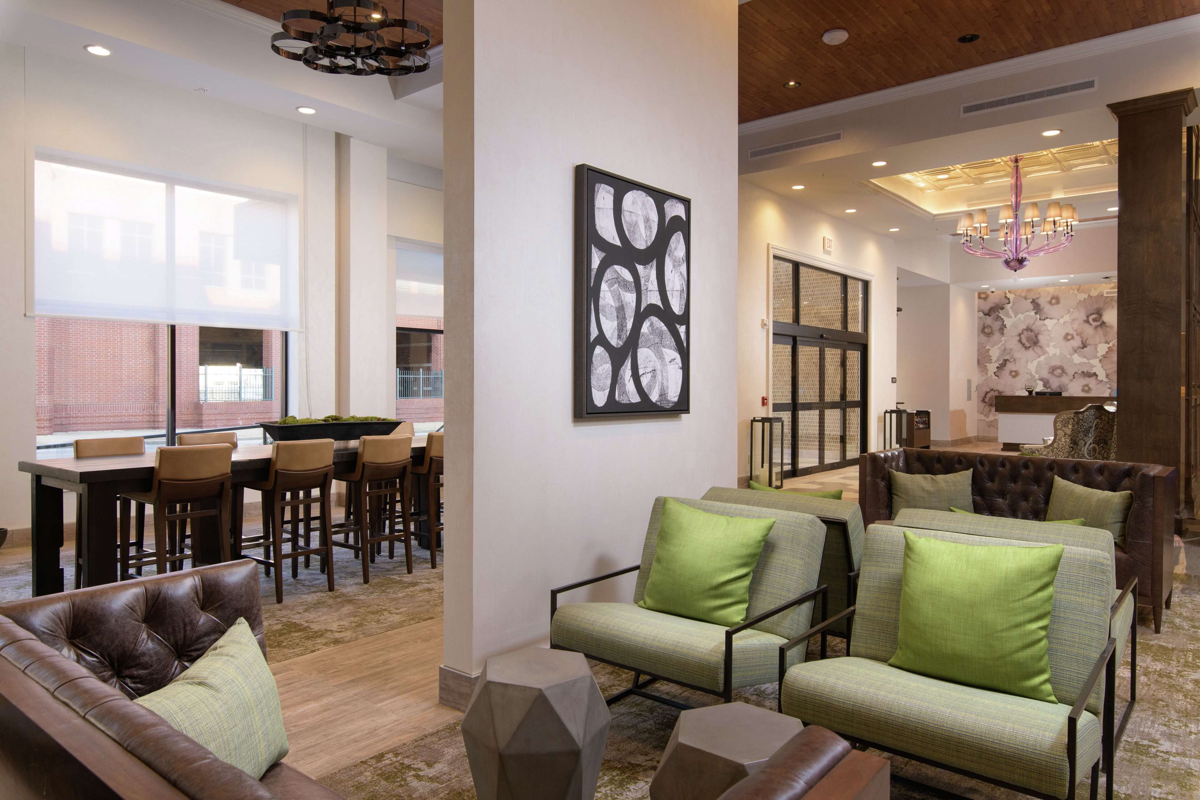 A spacious living area with a dining setup, a large abstract painting, and a chandelier.