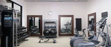 A gym with various exercise equipment, including treadmills, elliptical machines, and free weights.