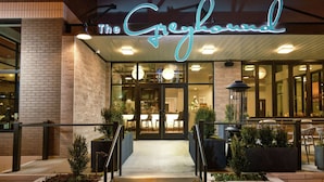 The exterior of The Greyhound restaurant with a neon sign, outdoor seating, and a brick facade. - Hilton Garden Inn Memphis Downtown Beale Street (Memphis)