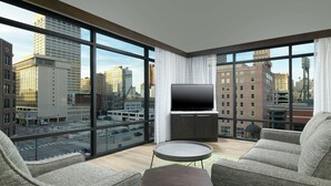 A modern hotel room with large windows, a flat-screen TV, and comfortable seating. - Hilton Garden Inn Memphis Downtown Beale Street (Memphis)