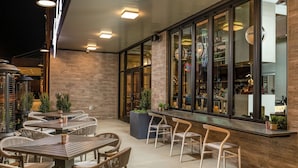An outdoor patio area with tables and chairs, a bar counter, and large windows. - Hilton Garden Inn Memphis Downtown Beale Street (Memphis)