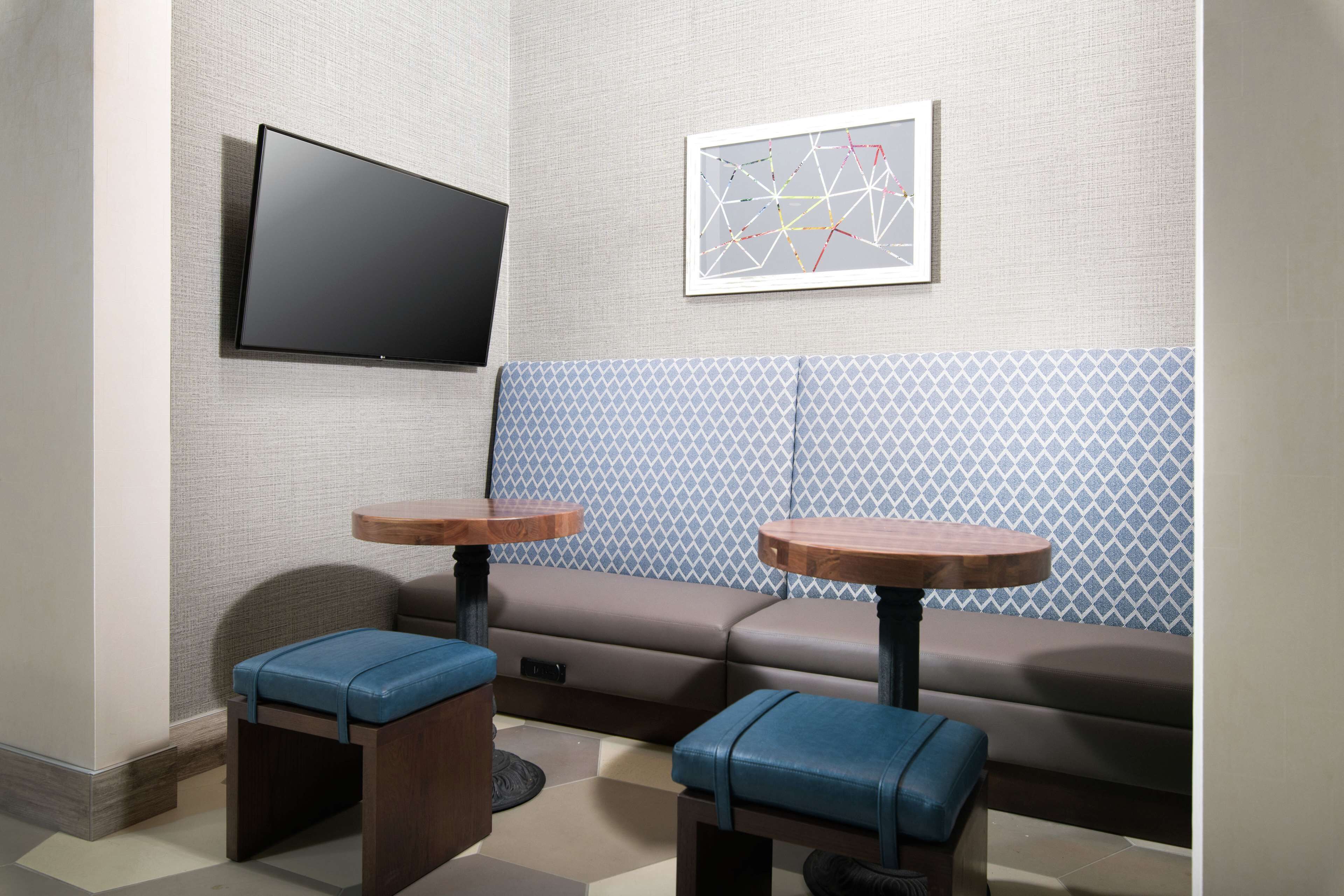 A modern room with a sofa, two small tables, a flat-screen TV, and a patterned wall.