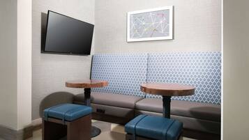 A modern room with a sofa, two small tables, a flat-screen TV, and a patterned wall.