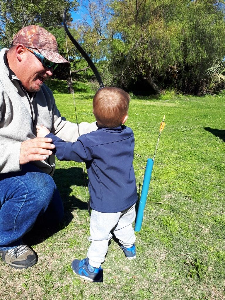 A person sitting outdoors with a child holding a stick.