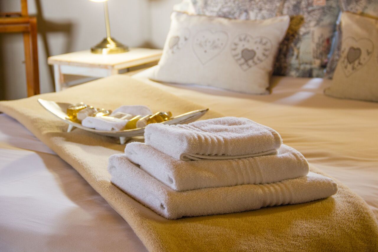 A neatly made bed with folded towels and a tray of toiletries.