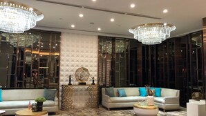 A modern lobby with two sofas, round coffee tables, and a decorative wall with geometric patterns. - Three Central (Makati)