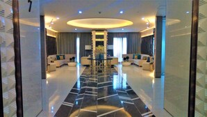 A spacious lobby with a central round table, sofas, and a reflective floor. - Three Central (Makati)