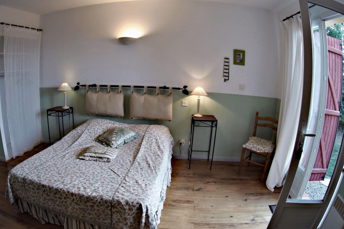 A bedroom with a bed, two bedside tables, a chair, and a window with curtains.