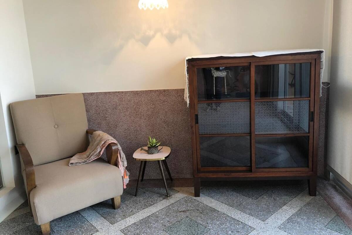 A corner room with a sofa, a small table with a plant, and a cabinet with glass doors.