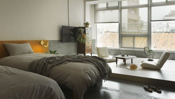 A modern bedroom with a large bed, a desk, a chair, and a view of the city through large windows. - La Maisonnette Tainan No.2 (Tainan)