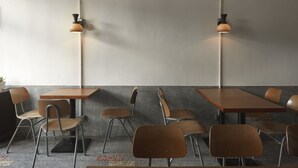A modern dining area with wooden tables and metal chairs, two pendant lights, and a textured wall. - La Maisonnette Tainan No.2 (Tainan)