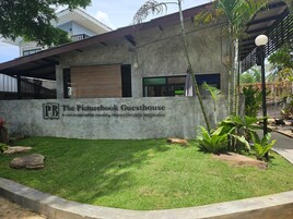 Un edificio con un cartel que dice "The Picturebook Guesthouse" y un césped bien cuidado.